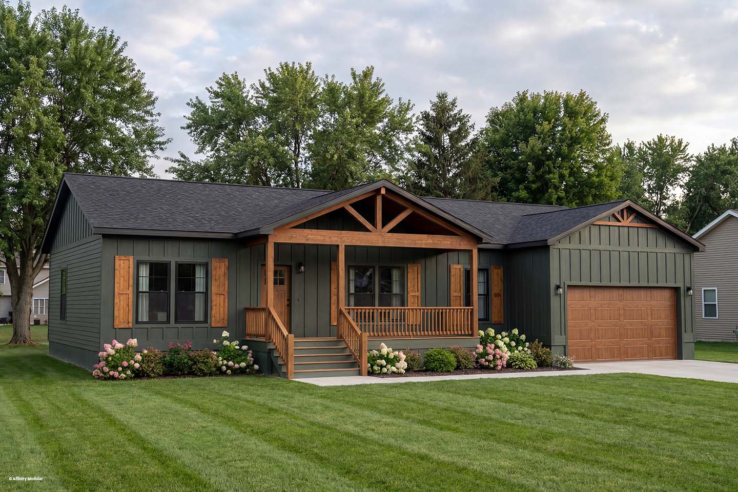 Single-story modular home with dark siding, wood accents, front porch, and attached garage, surrounded by a green lawn.